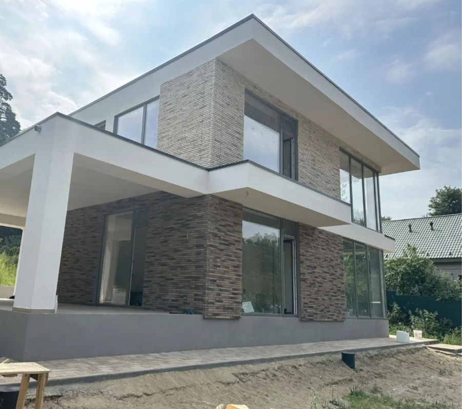 Дом облицованный декоративным кирпичом "Реген Брик" коричневый 690-40, 690-45, "Реген Брик" молочный 694-10, 694-15 (White Hills). Крепится к стене на клей White Hills "Экстра". Для швов использована затирка серая, белая (White Hills).