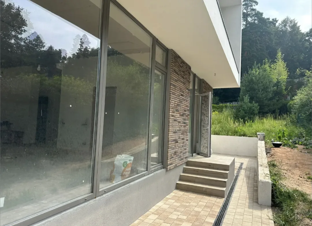 Дом облицованный декоративным кирпичом "Реген Брик" коричневый 690-40, 690-45, "Реген Брик" молочный 694-10, 694-15 (White Hills). Крепится к стене на клей White Hills "Экстра". Для швов использована затирка серая, белая (White Hills). Раскладка брусчатки Steingot Новый город "Травертин", бордюр садовый 1000*200*80 "Травертин".