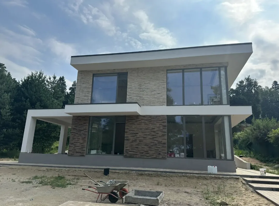 Дом облицованный декоративным кирпичом "Реген Брик" коричневый 690-40, 690-45, "Реген Брик" молочный 694-10, 694-15 (White Hills). Крепится к стене на клей White Hills "Экстра". Для швов использована затирка серая, белая (White Hills).